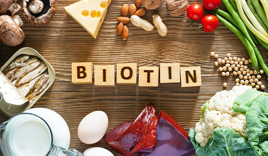 Iz lesenih kock izpisano Biotin, okoli napisa hrana bogata z biotinom