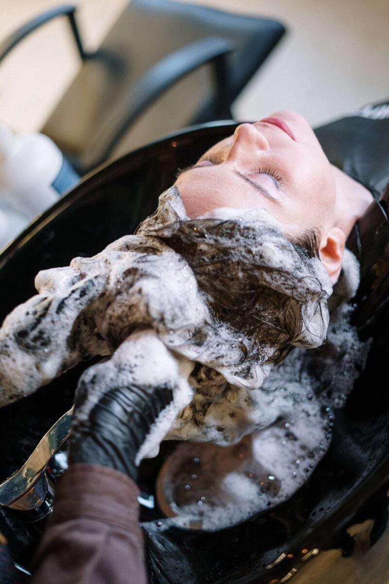 Ženska pri frizerju leži, umivajo ji lase